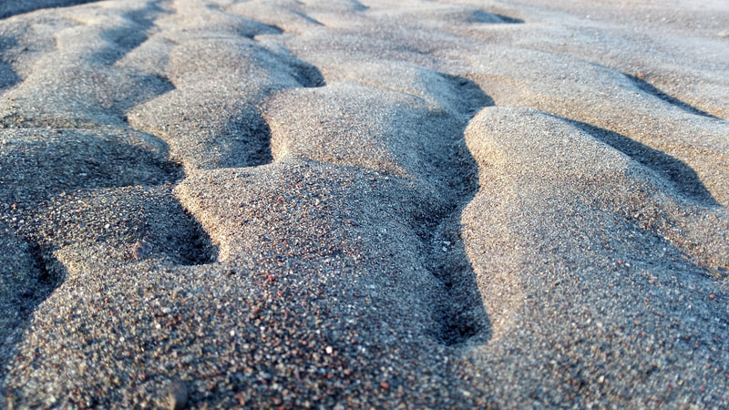 The rhythmic ripples in the sand left by the Columbia River, and the colorful, intricate sand illuminated by the setting sun, Sauvie Island, Oregon. February 2022