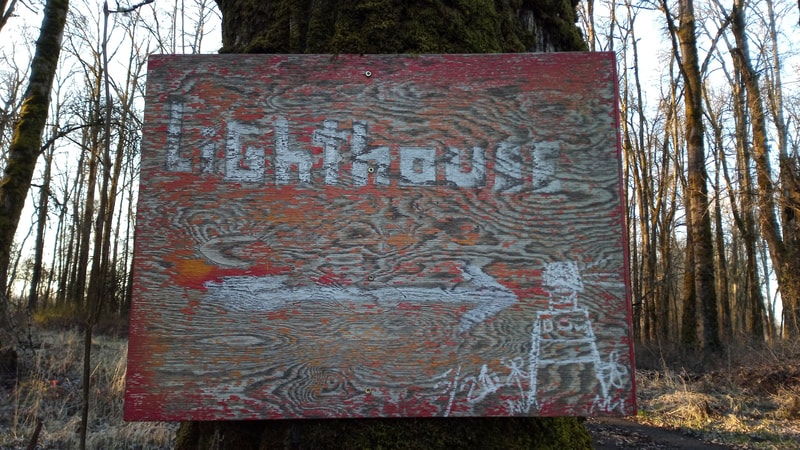 A wonderful, hand-crafted, artistic wood sign on a tree, guiding visitors to the Sauvie Island Lighthouse on the northern tip of the island, February 2022
